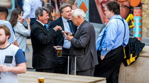 Getty Images A group of businessmen standing outside England in the Shipwrights Arms pub tavern drinking beer from glasses.